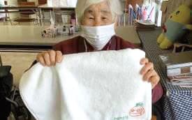 刺繍を施したタオルを持つ高齢者施設利用者の方